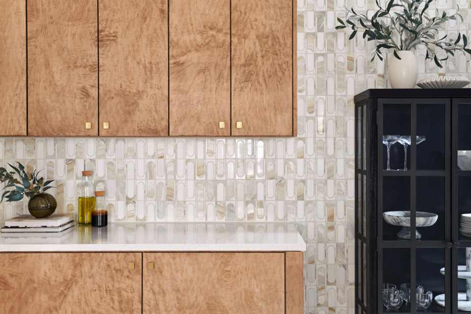 mosaic accent wall in kitchen with wood cabinetry and decorative plants